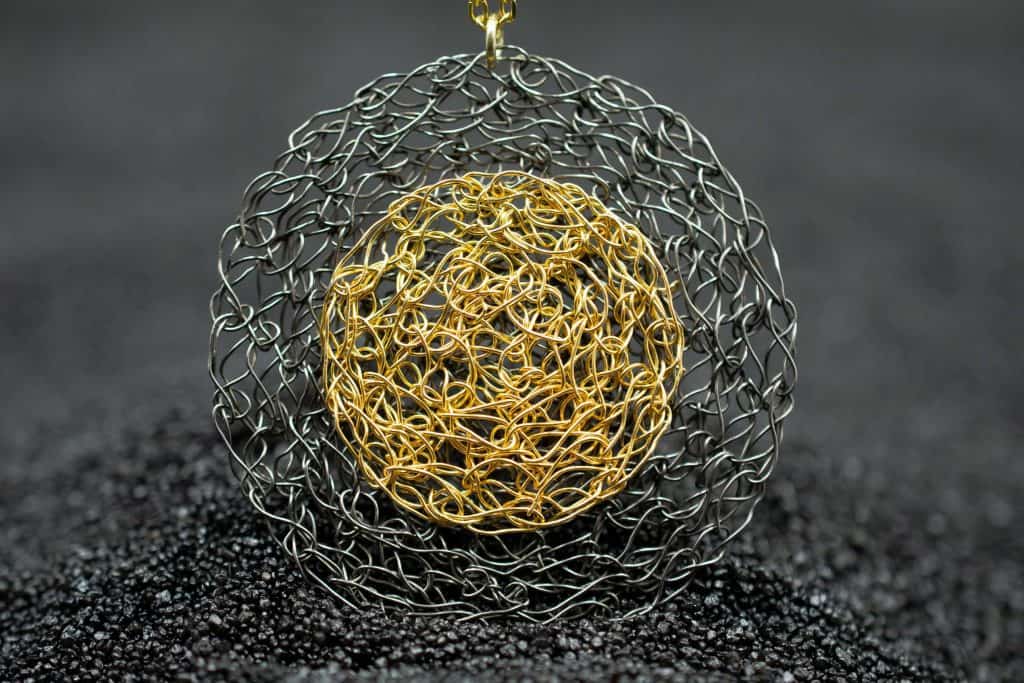 detail of gold disc necklace on lava background