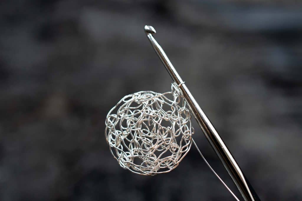 detail of a crochet needle and a handmade silver circle